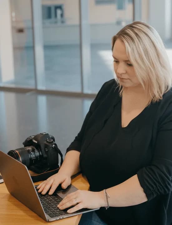 Eva Czaja arbeitet am Laptop, neben ihr liegt eine Kamera