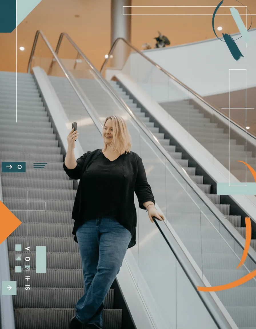 Eva Czaja fährt lächelnd eine Rolltreppe hinunter und hält ihr Smartphone